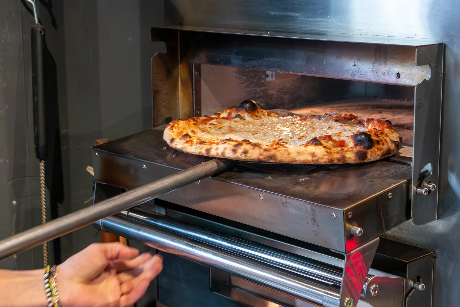 Una pizza entrando al horno en Salvo Pan y Pizza, Barrio 28, Valle de Bravo