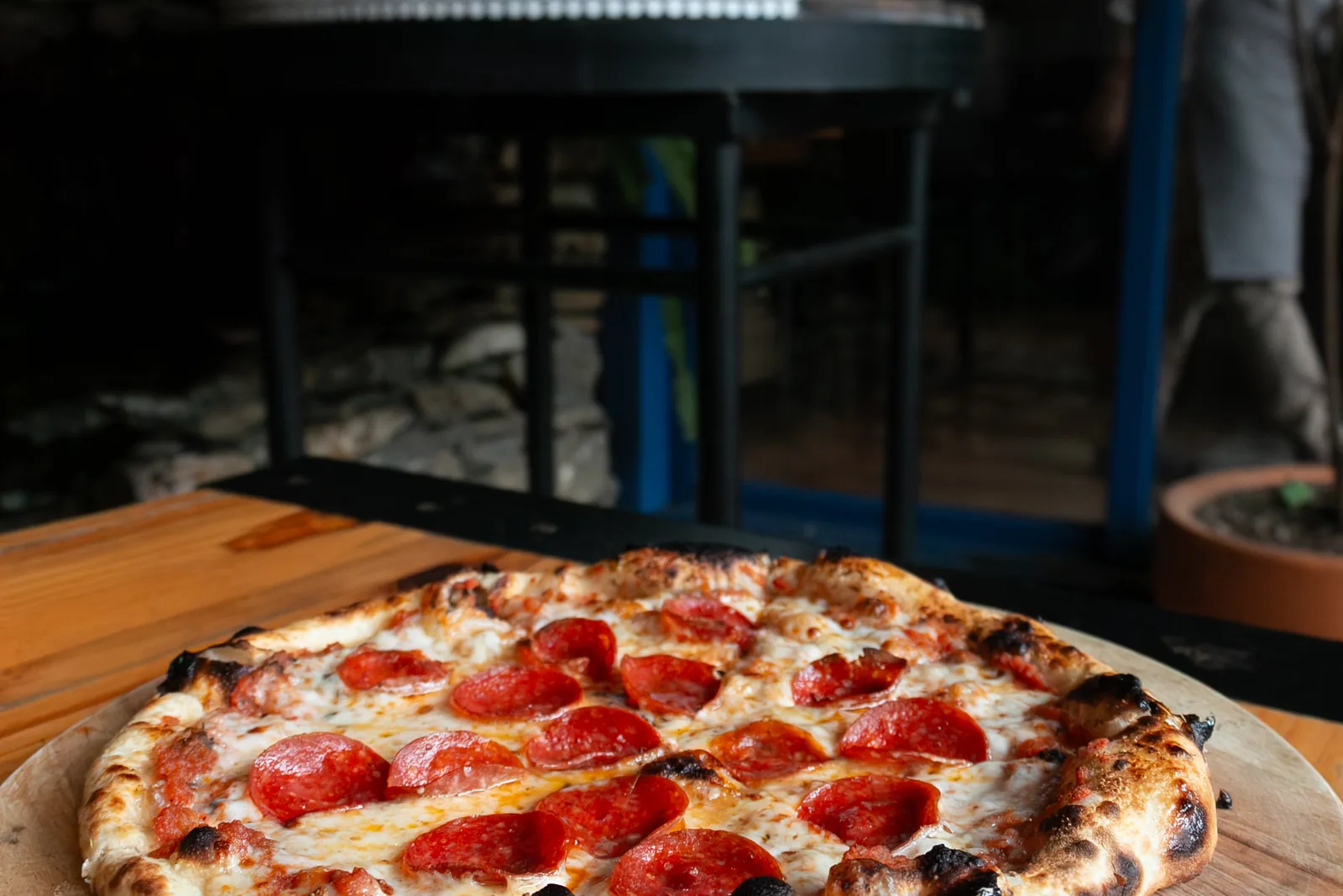 Pizza individual de pepperoni recién horneada sobre tabla de madera